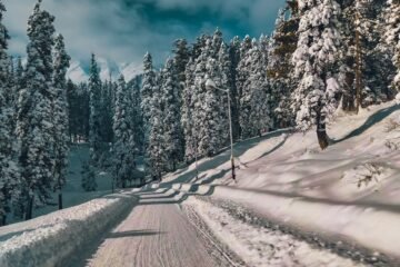 a person riding a snowboard down a snow covered road