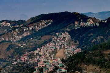 Panoramic view of Munsiyari with lush green meadows and towering Himalayan mountains in Uttarakhand.